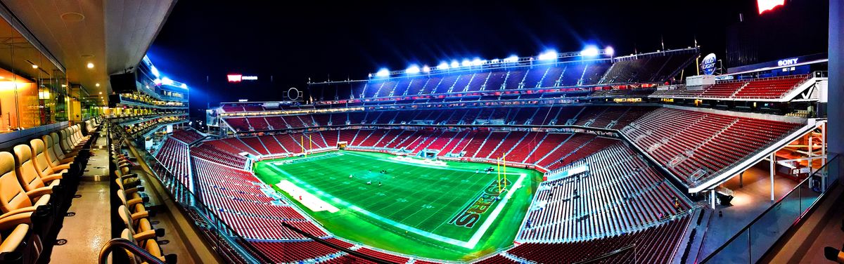 Floodlit American football stadium filled with spectators at night